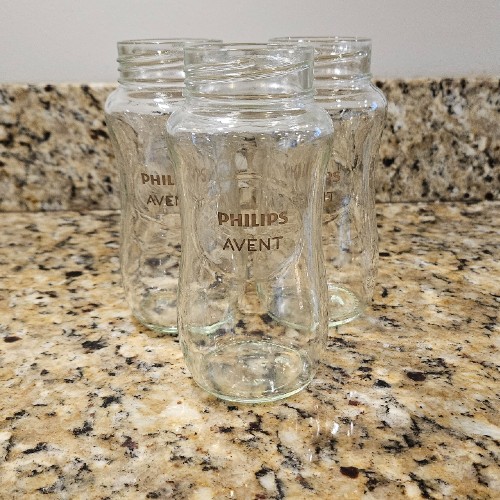 3 Philips Avent glass baby bottles on kitchen countertop.